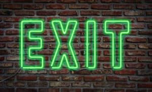 Glowing neon "exit" sing on a brick wall.